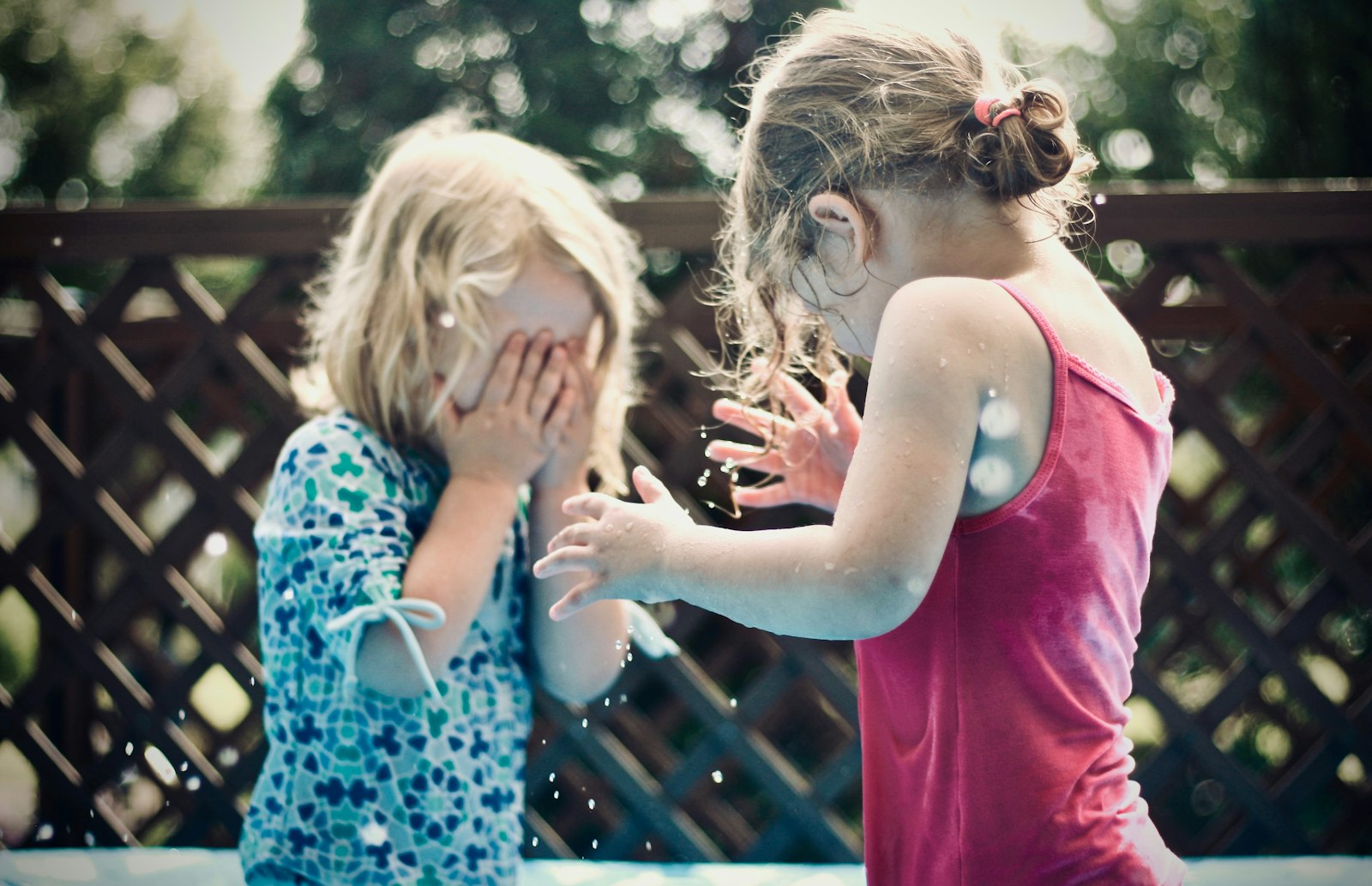 two children playing water during daytime shallow focus photography how to teach kids to bounce back