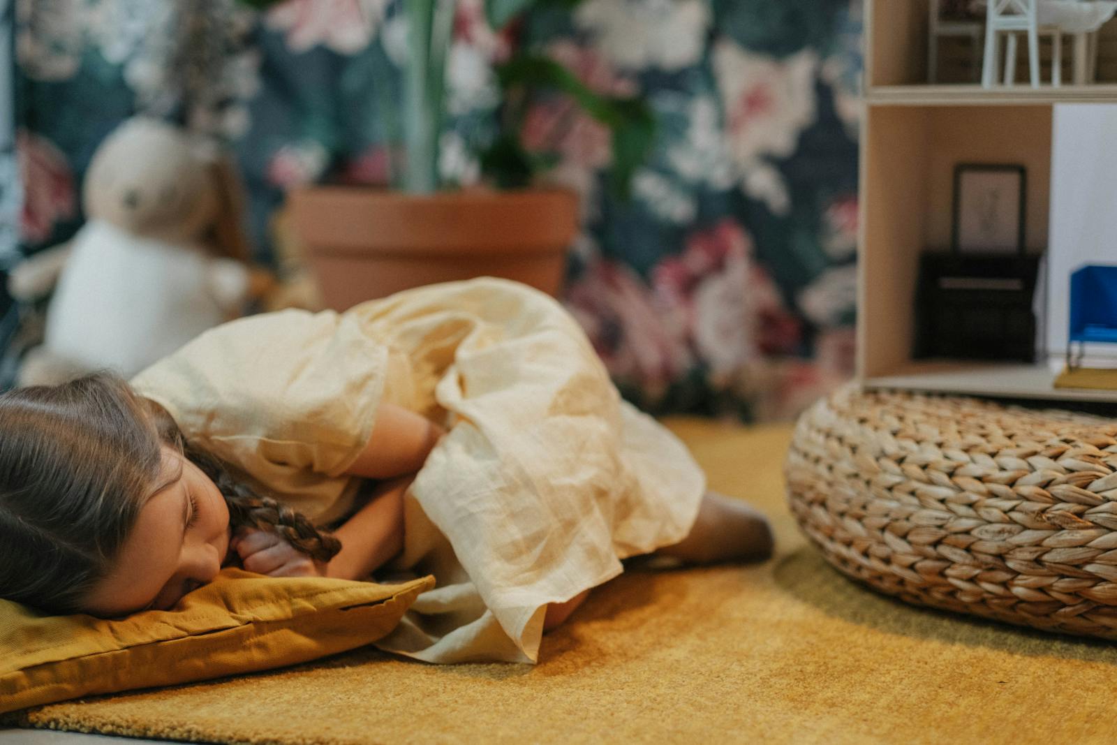 A young girl in a yellow dress peacefully asleep indoors next to a dollhouse and wicker ottoman. What is co-regulation?