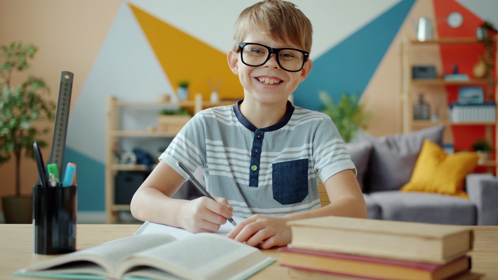 Smiling boy wearing glasses studying at a desk. leadership skills for kids